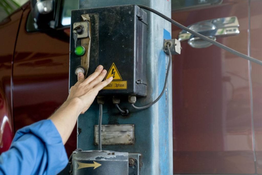 Close up hand push the button of car lifting machine in workplace of  garage.