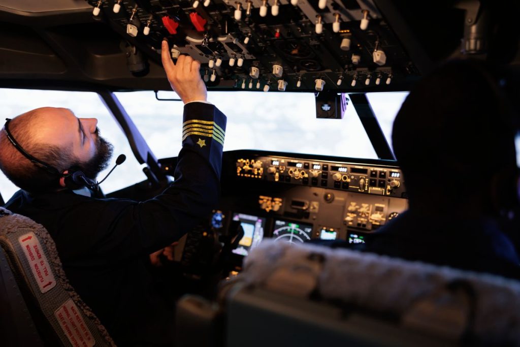 Male captain pushing buttons to start power on dashboard control, using panel command in cabin to fly airplane. Aircrew flying aircraft jet with radar compass and aerial navigation.