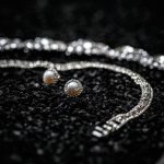 Silver bracelet and necklace with diamonds, earrings with pearl on black background