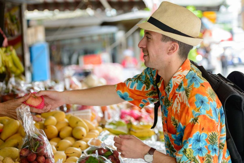 Portrait of young handsome tourist man at the street market outdoors