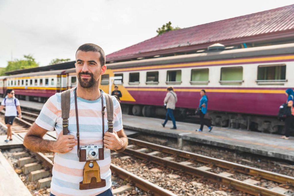 Tourist with camera at train station in Ayutthaya, Thailand - Young man travelling  in Thailand and waiting for a train - Tourism and travel concepts.