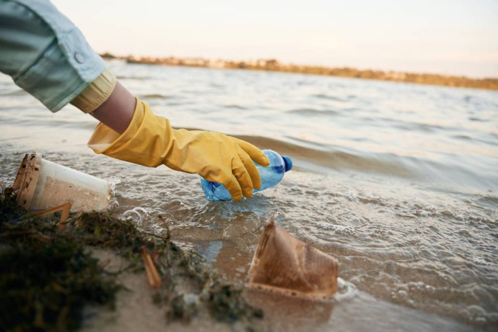 Close up view of female volunteer that is holding plastic bottle, trash pollution