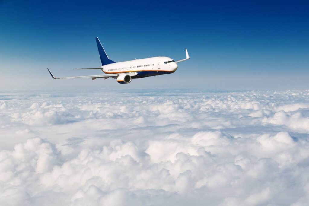 Commercial airplane flying above clouds on blue sky background