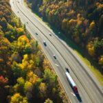 I-40 freeway road leading to Asheville in North Carolina over Appalachian mountain pass with yellow fall forest and fast moving trucks and cars. Concept of high speed interstate transportation.