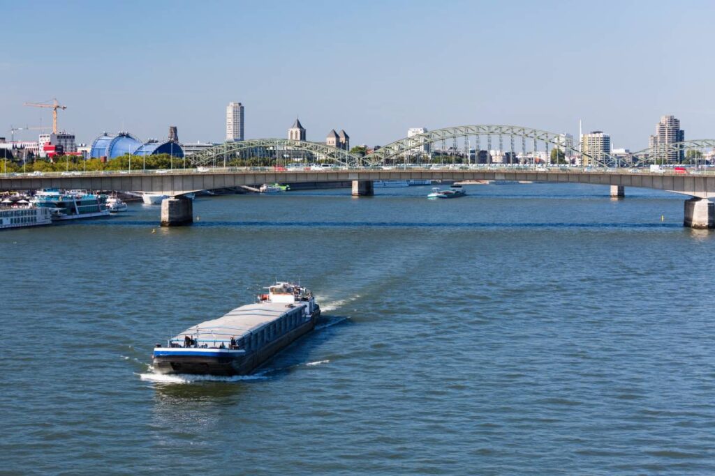 A ship on Rhine River in Cologne, Germany in front of the Hohenzollern Bridge and Deutzer Bridge
